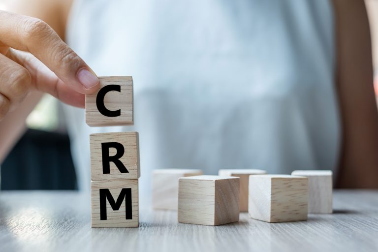CRM solutions. Hand holding blocks spelling out "CRM"